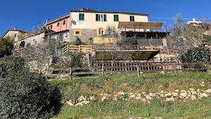 A multi-story building with a stone facade, green shutters, and a balcony. - Agriturismo Mamma Chica (La Spezia)