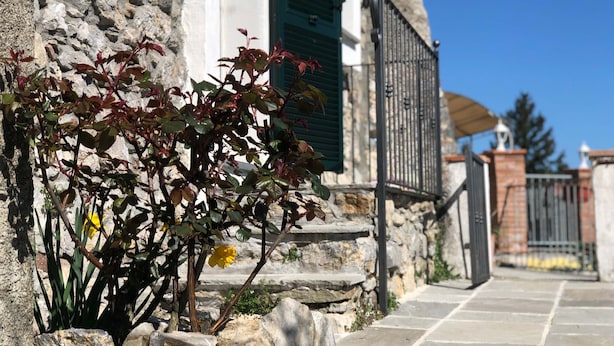 A stone building with a stone staircase leading to a gated entrance. - Agriturismo Mamma Chica (La Spezia)