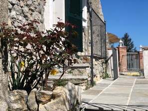 A stone building with a stone staircase leading to a gated entrance. - Agriturismo Mamma Chica (La Spezia)
