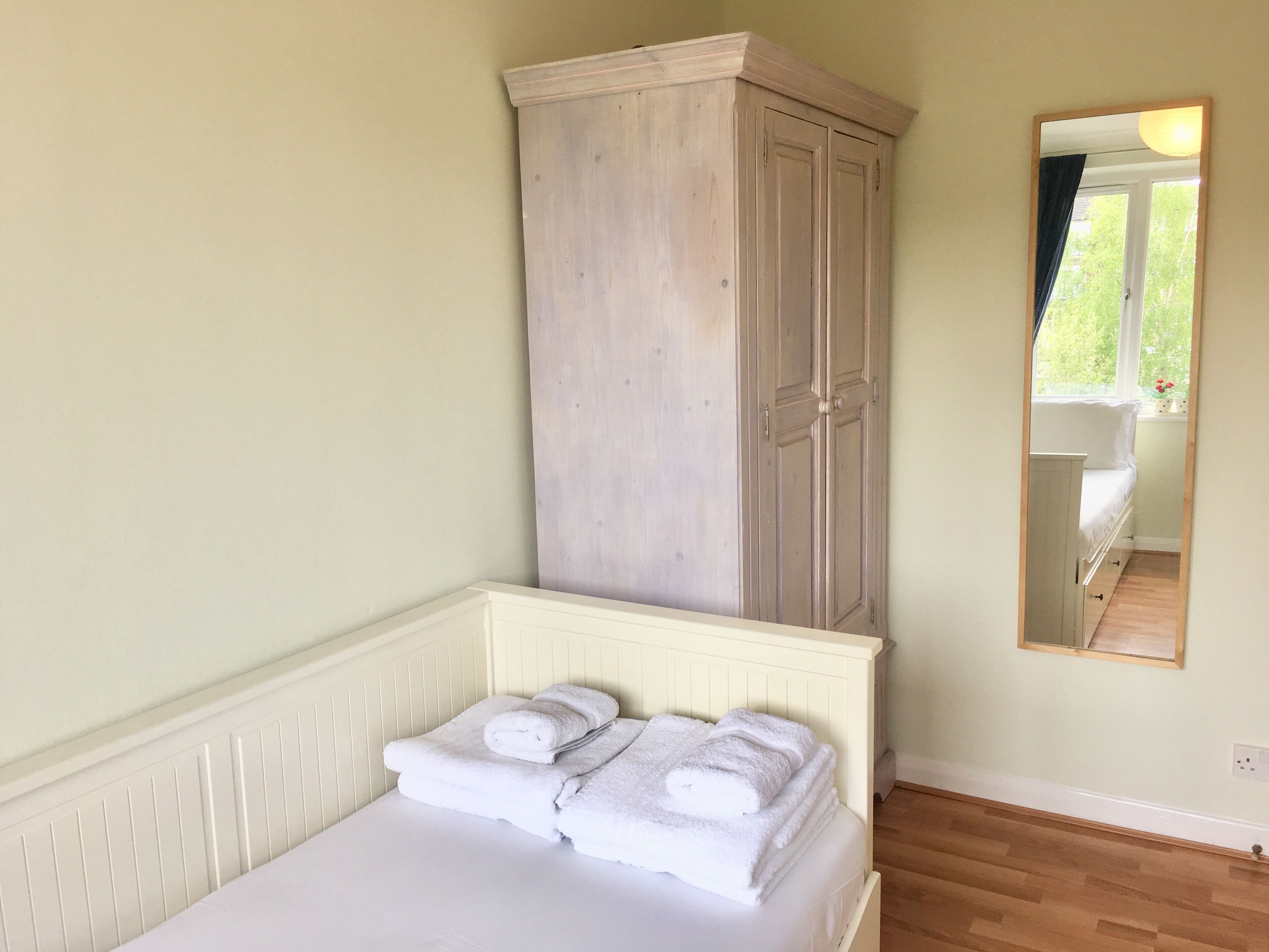 Un dormitorio con cama, armario y espejo.