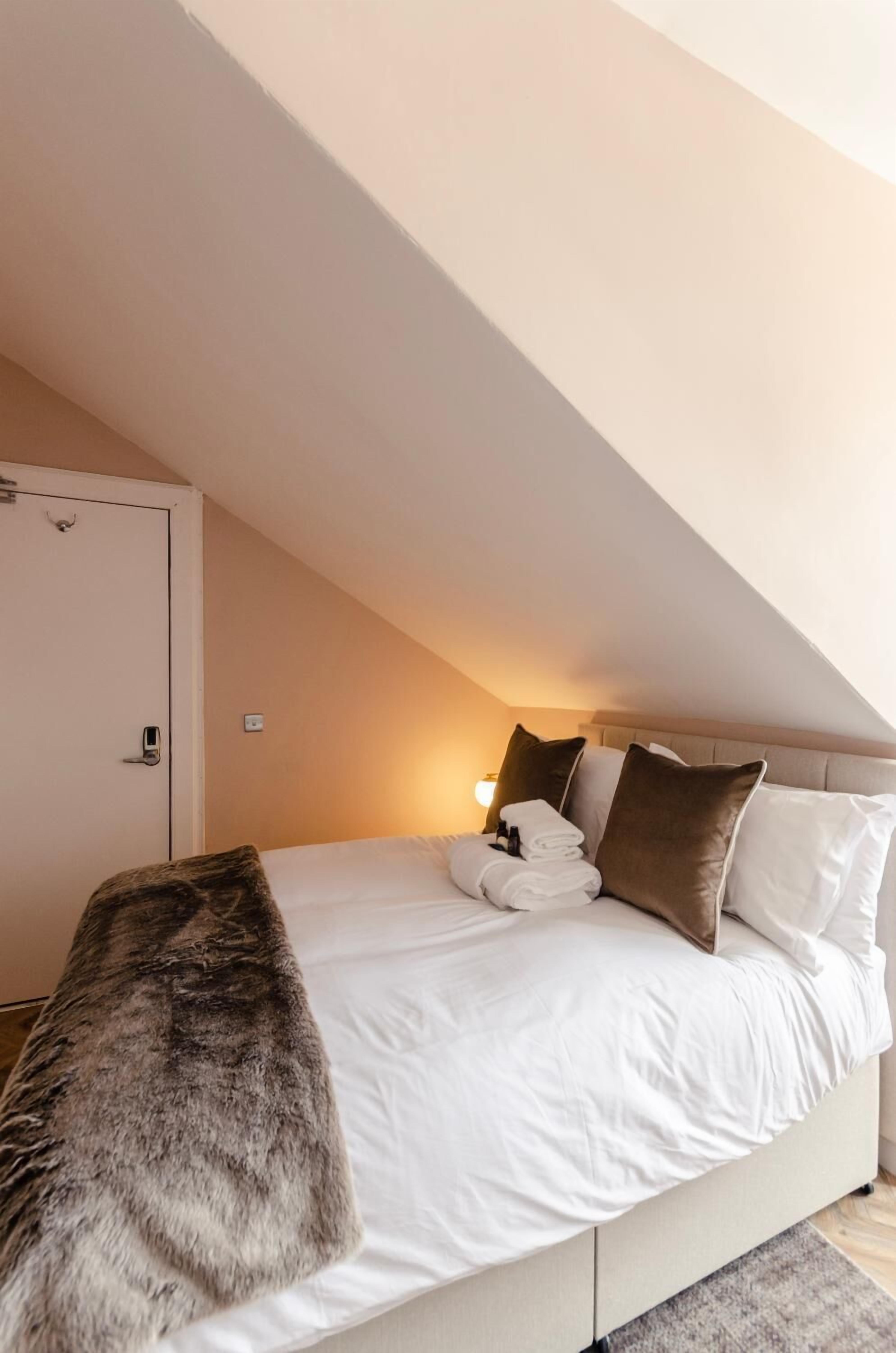 A bedroom with a bed, pillows, a blanket, and a door.