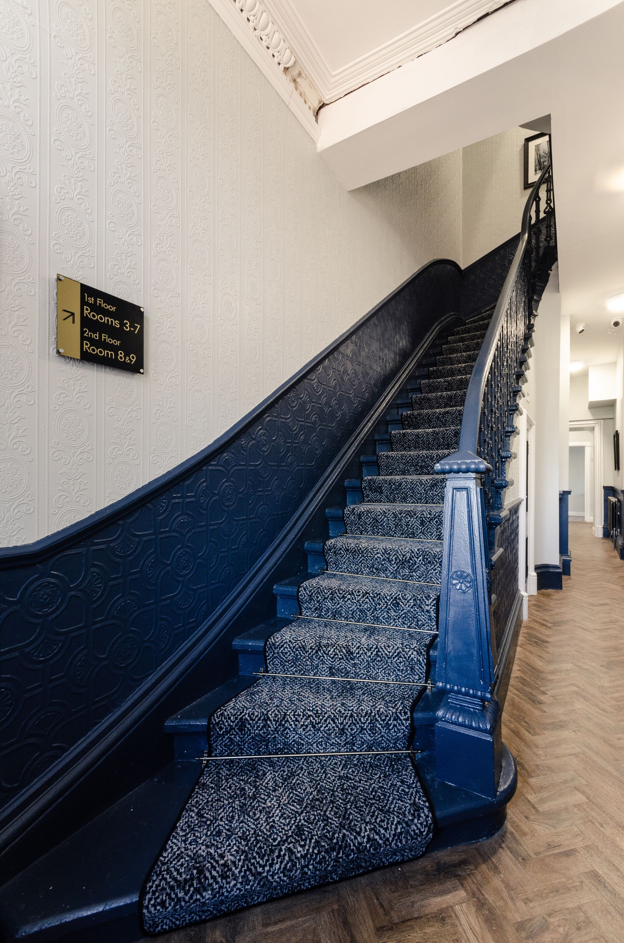 A staircase with a black handrail and patterned carpet, leading to multiple floors.