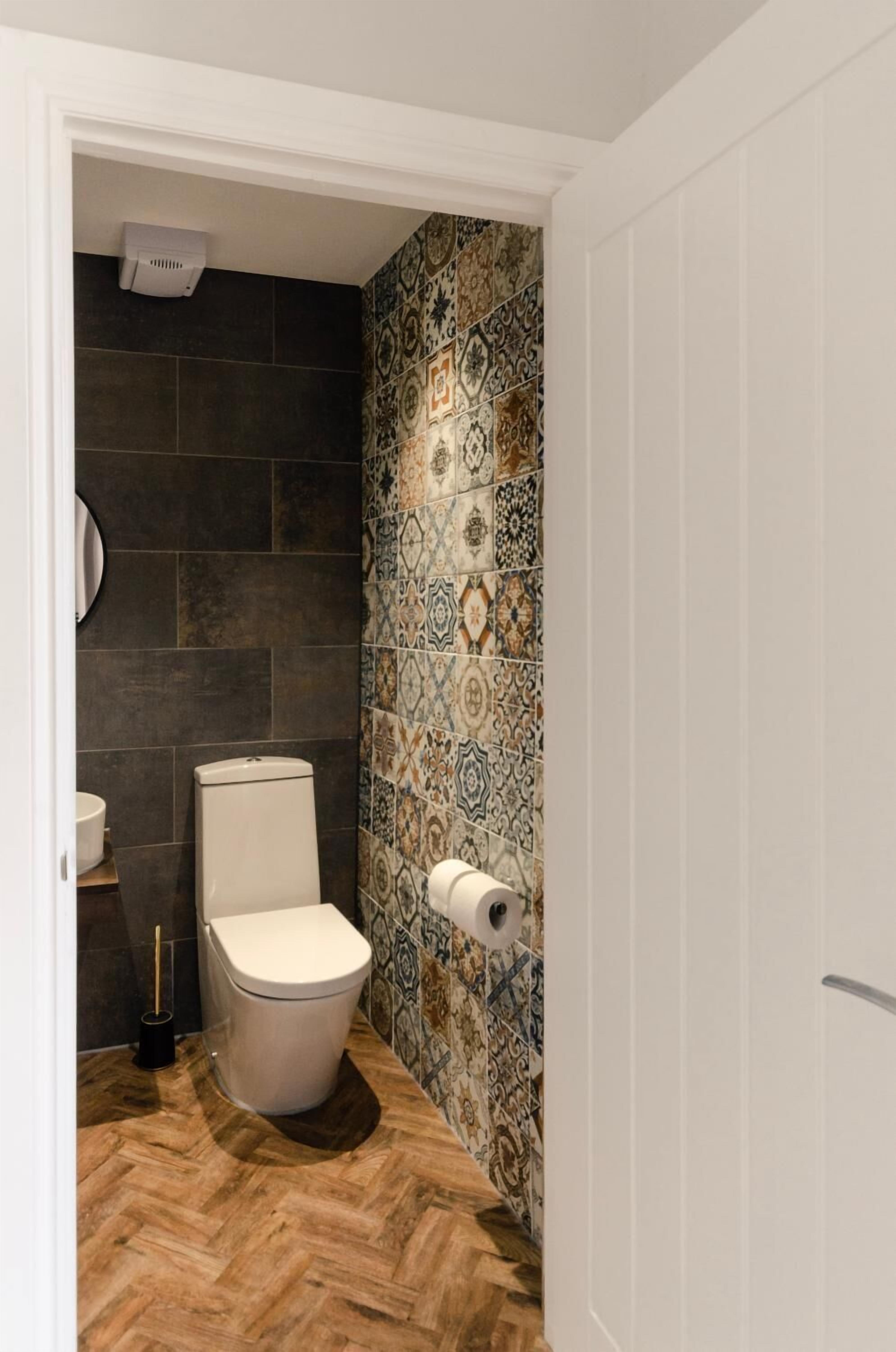 Casa de banho com sanita, suporte para papel higiénico e purificador de ar fixado na parede.