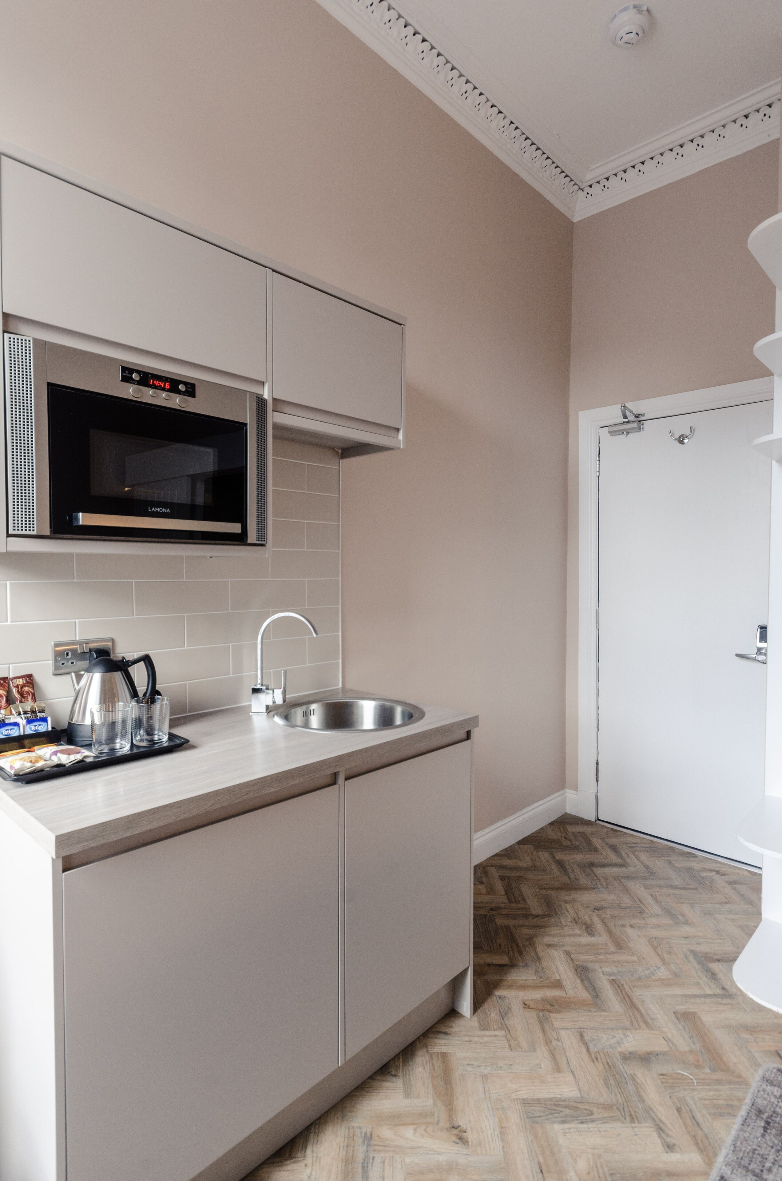 Cocina moderna con microondas, pileta y piso con patrón de espiga.
