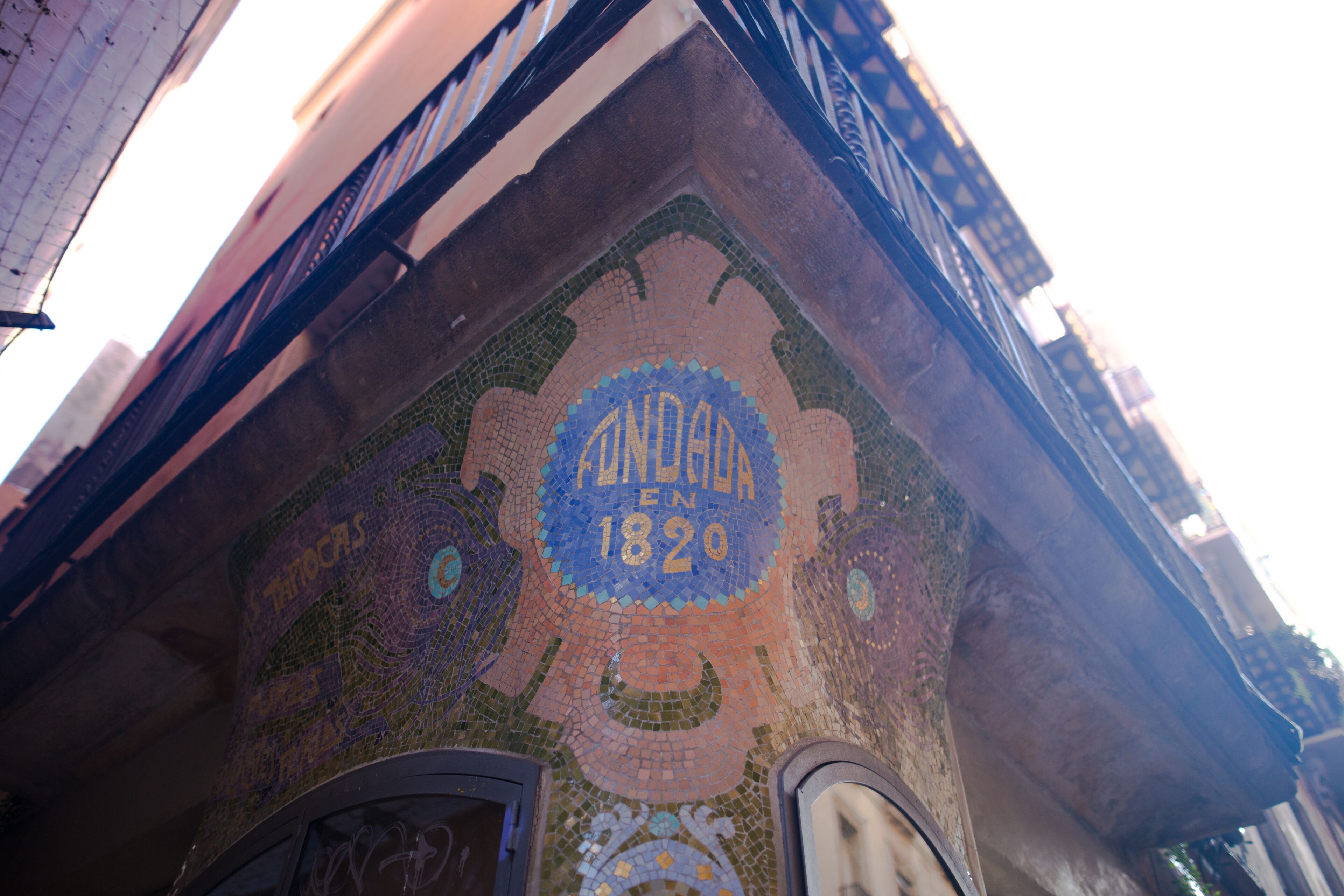 A building corner with a mosaic tile design and a sign reading "ANDARAN 1820".