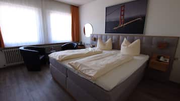 Una habitación de hotel con una cama grande, un escritorio, una silla, un ventanal con cortinas y un cuadro de un puente.