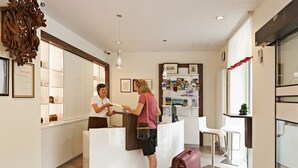 A reception area with a white counter, framed certificates, and a large wooden clock.