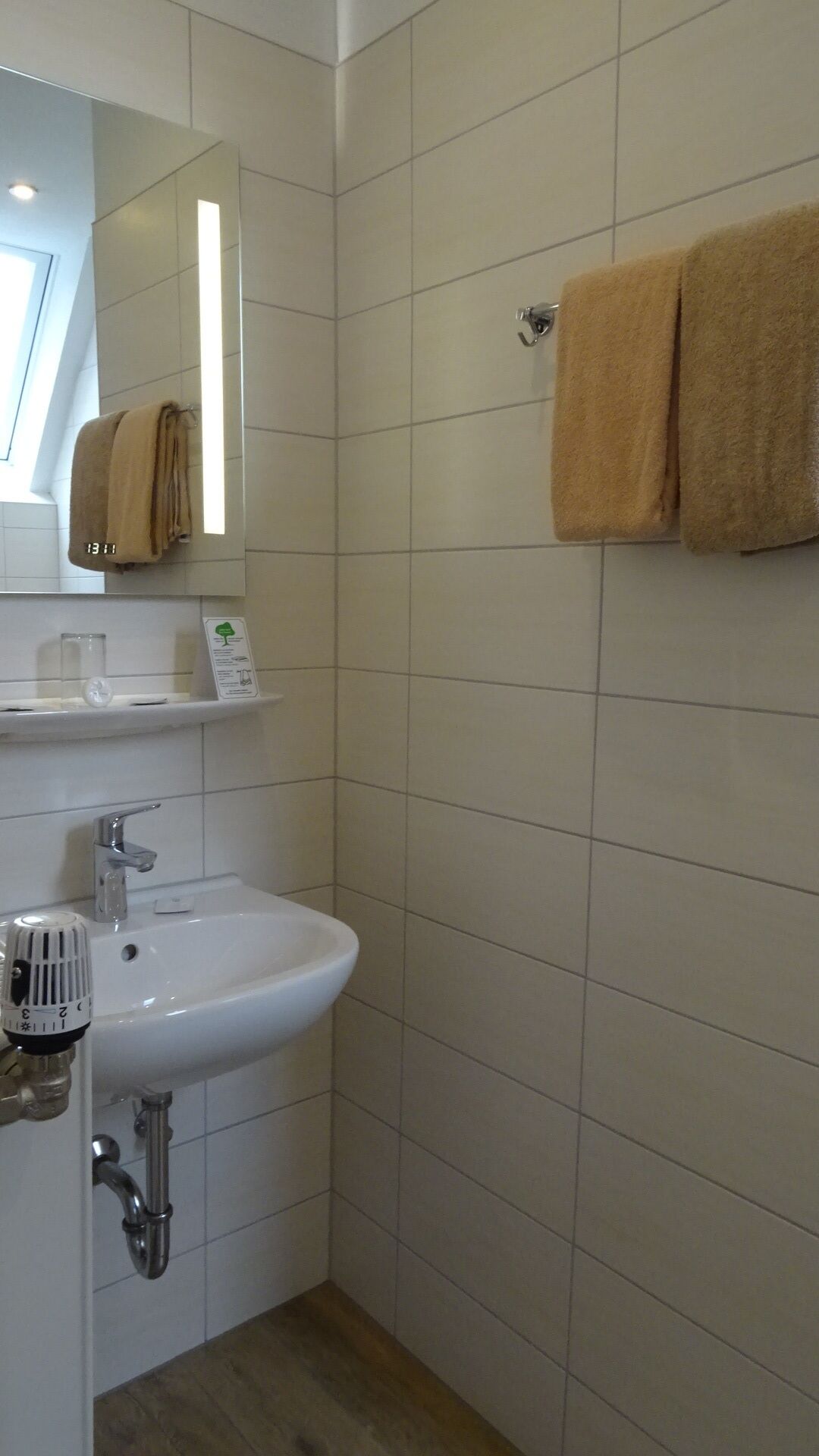 A bathroom with a white sink, a mirror, and two towels hanging on a towel rack.