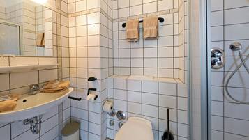 A bathroom with a sink, mirror, toilet, and shower.