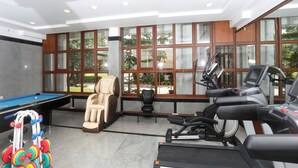 A gym with exercise equipment including treadmills, a massage chair, and a pool table. - Holiday Valley Nature Resorts (Denkanikota)