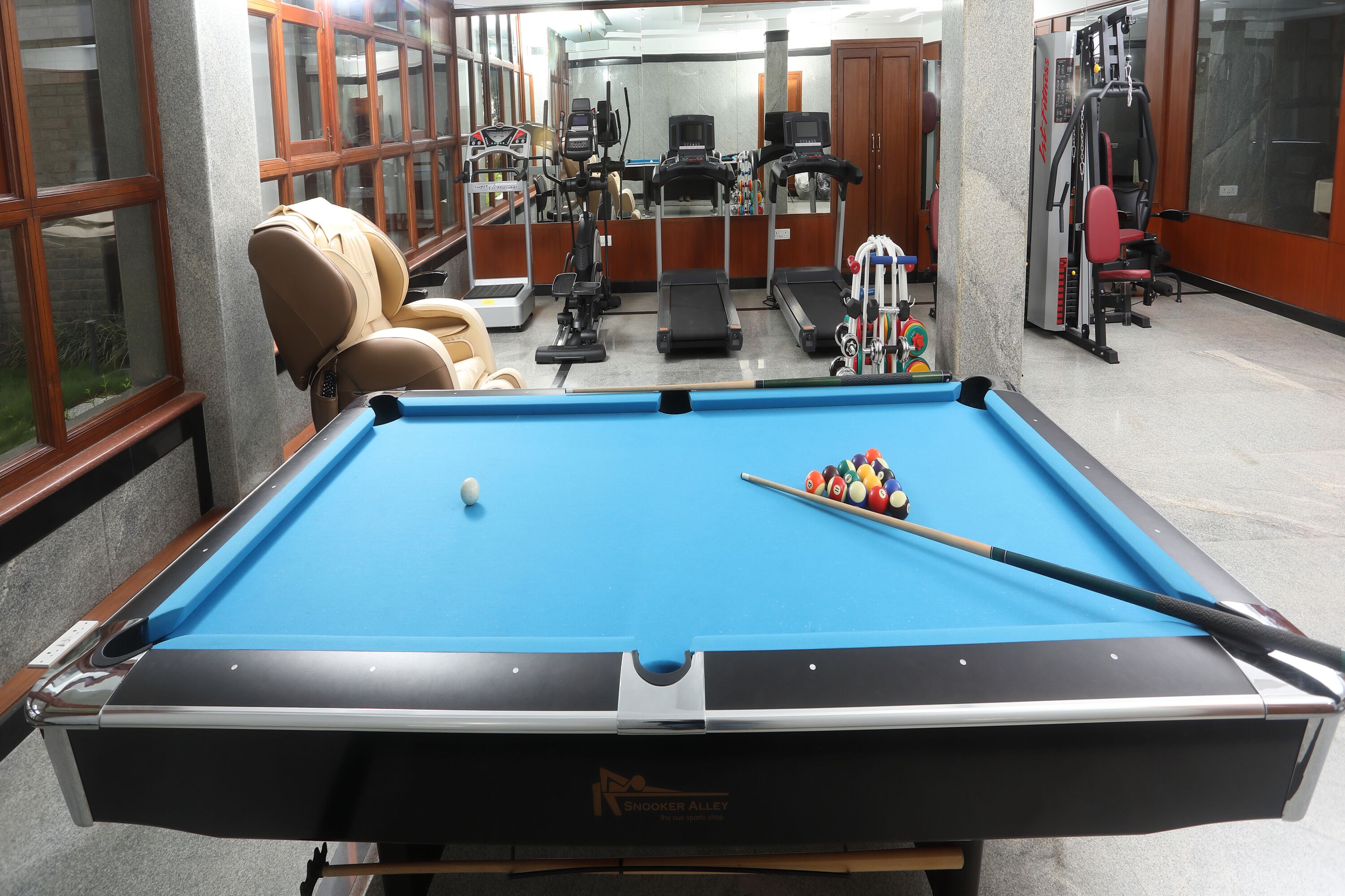 A pool table with a blue felt surface, a cue stick, and billiard balls.