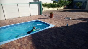A rectangular swimming pool with a child swimming inside. - Welterusten Guesthouse (Cape Town)