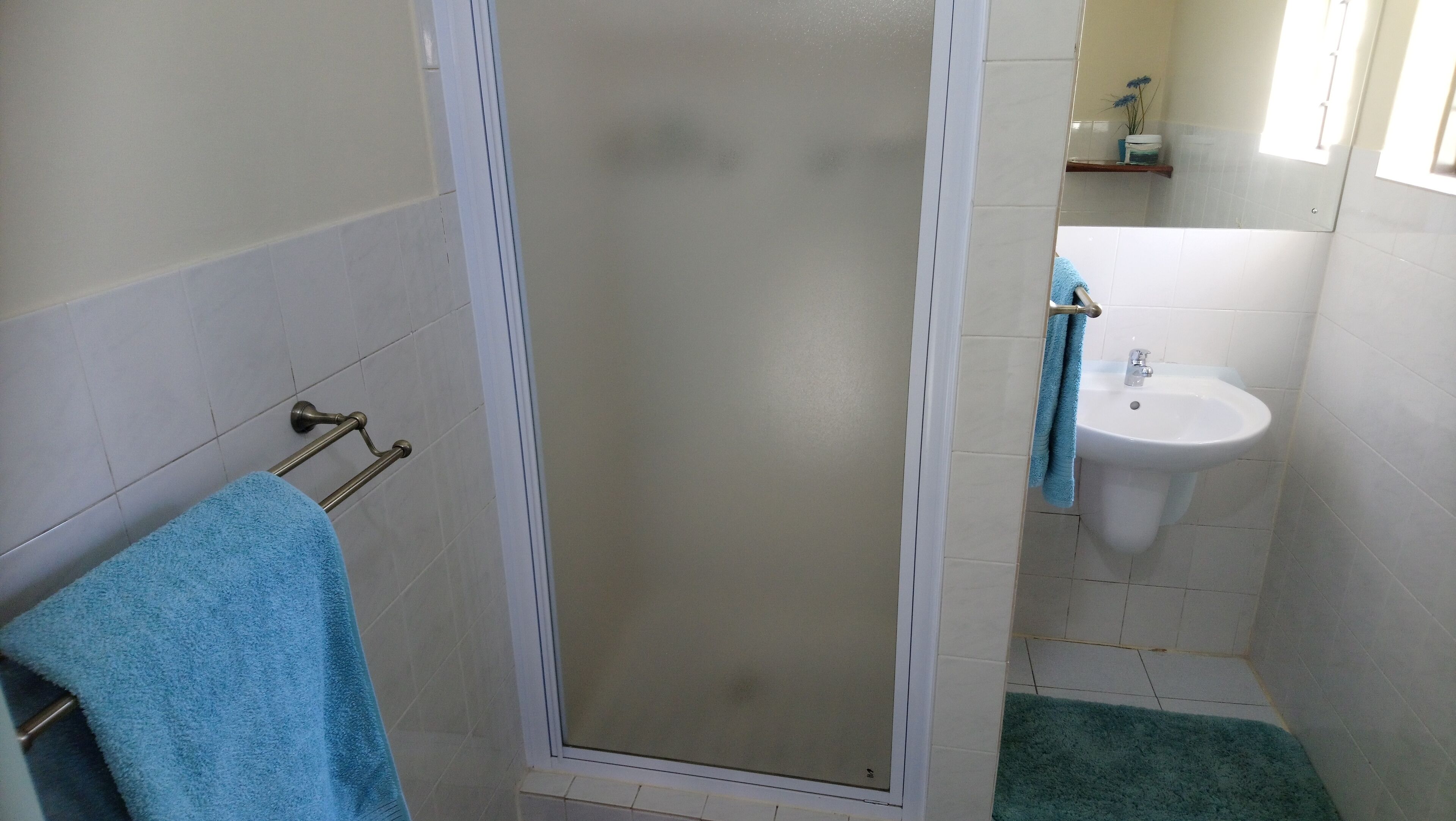 Une salle de bain équipée d’une douche, d’un lavabo et d’un porte-serviettes.
