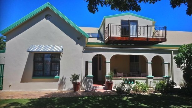 A two-story building with a balcony, a covered porch, and potted plants. - Welterusten Guesthouse (Cape Town)