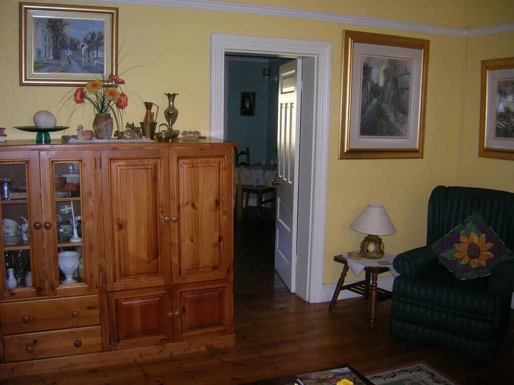 A living room with wooden cabinets, a green armchair, and a small table with a lamp.