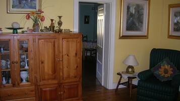 A living room with wooden cabinets, a green armchair, and a small table with a lamp.