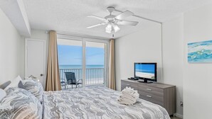 Une chambre avec un lit, une télévision, un ventilateur de plafond et une vue sur l’océan.