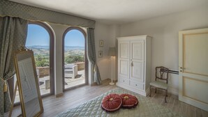 A room with a large arched window, a white wardrobe, a wooden chair, and a quilted bedspread. - Torresassa, Montaione, Florence and Chianti (Montaione)