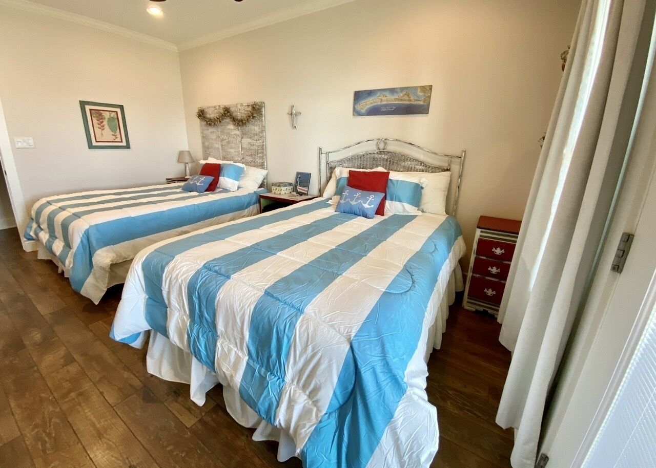 Une chambre avec quatre lits, chacun doté de draps bleus et blancs, d’un plancher en bois et d’une petite armoire rouge.