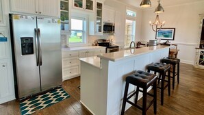 Une cuisine moderne avec des meubles blancs, des appareils en acier inoxydable et un îlot central doté de tabourets de bar.