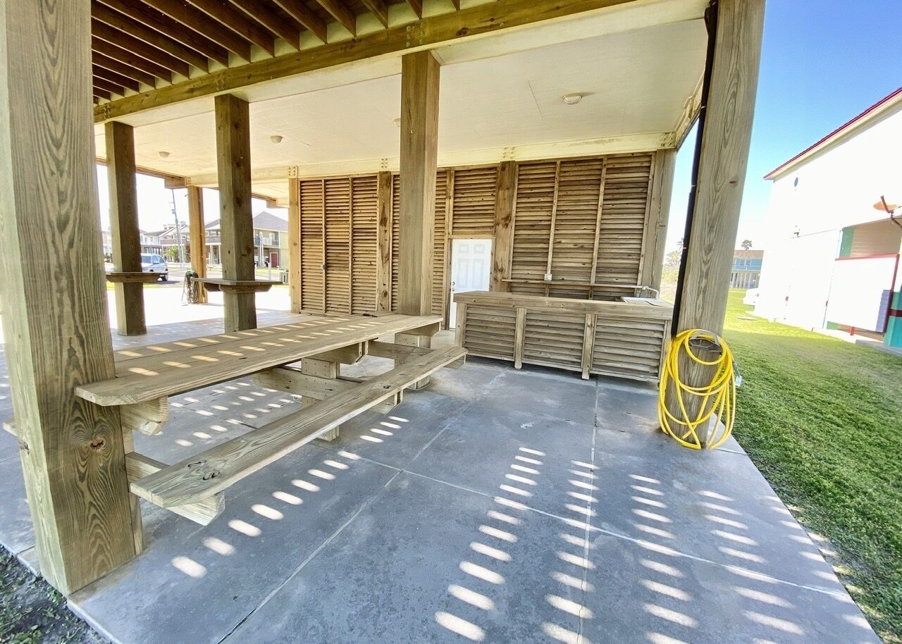 An outdoor covered seating area with wooden benches and a concrete floor.