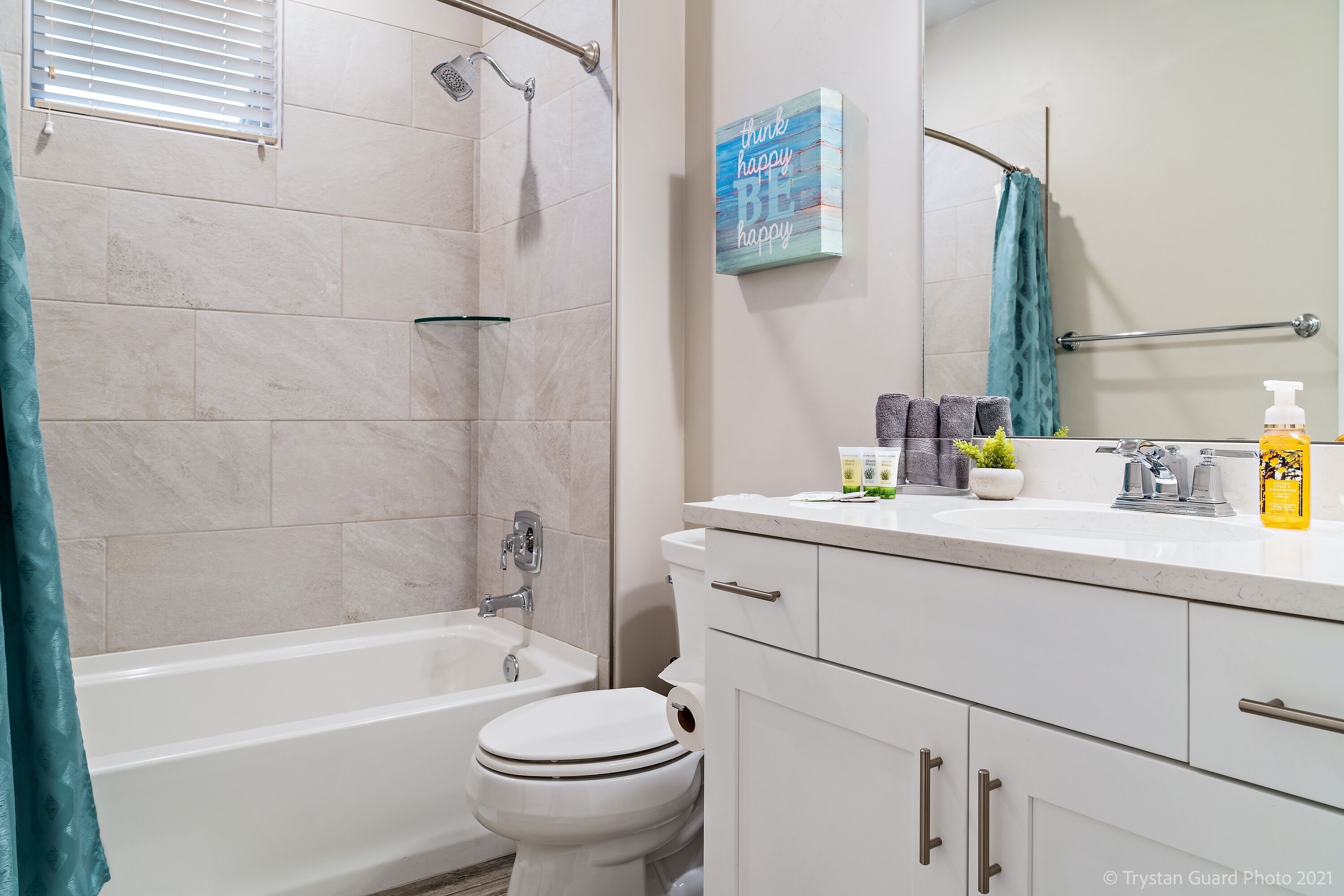 A modern bathroom with a bathtub, toilet, and a vanity with a mirror.