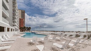 Un espace piscine avec des chaises longues, une piscine et une vue sur la plage.