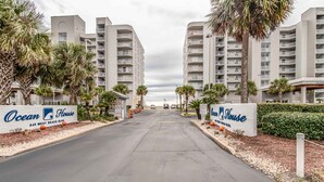 L’entrée d’un hôtel, avec deux immeubles imposants, des palmiers et une enseigne indiquant « Ocean House, 949 West Beach Blvd. ».