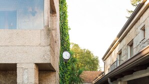 Un estrecho callejón empedrado flanqueado por edificios de piedra, con un reloj y macetas.