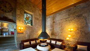 Un rincón acogedor con paredes de piedra, chimenea y asientos.