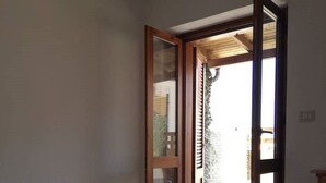 Ein Schlafzimmer mit einem Bett, einem Fenster und einer offenen Tür, die auf einen Balkon führt.