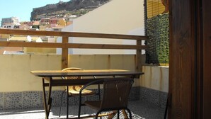 Ein Balkon mit Tisch und Stühlen mit Blick auf eine Stadtlandschaft, einschließlich Gebäude und einem Hügel.