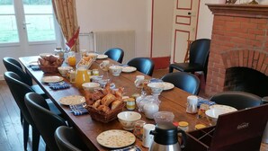 A dining table set for breakfast with various dishes, a coffee pot, and chairs around it.