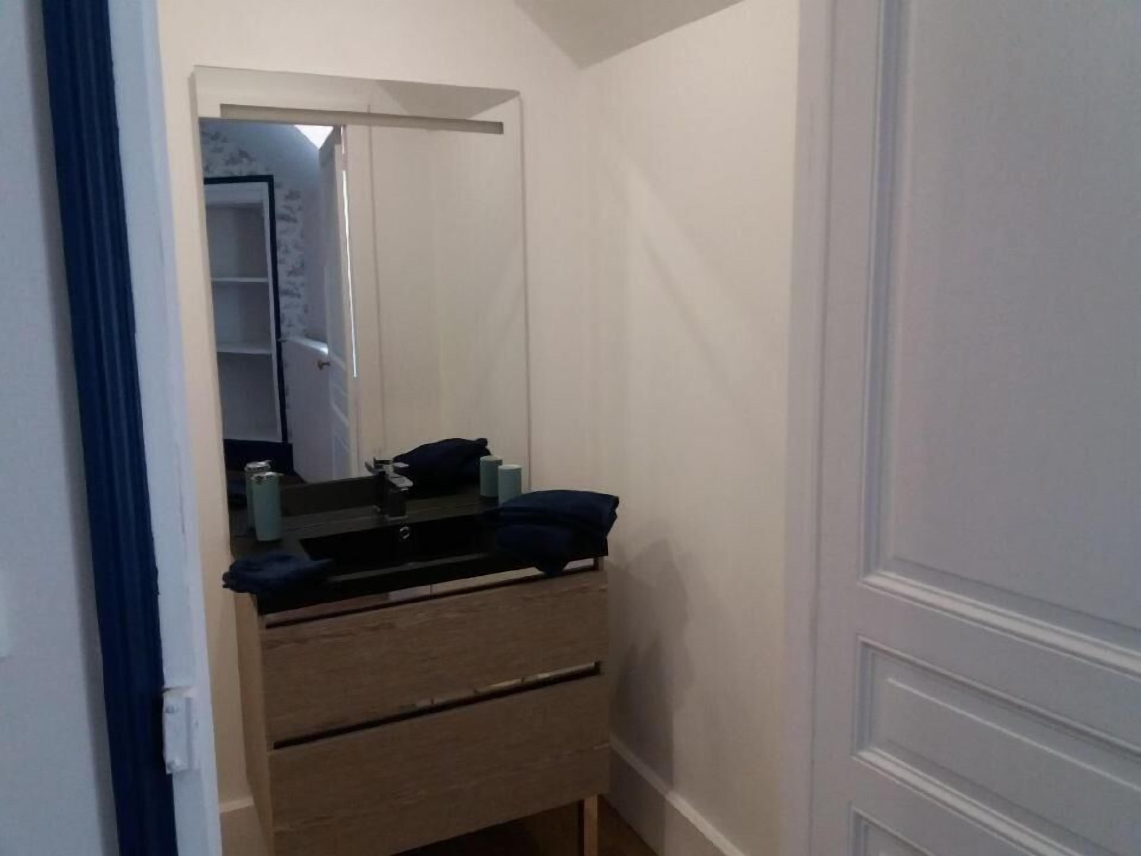 Un bagno piccolo e stretto con un mobiletto in legno, uno specchio e un asciugamano appeso al muro.
