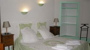 A neatly made bed with pillows and a duvet, two bedside lamps, a wooden nightstand, and a green wardrobe with a mirror. - Chateau de Chavannes (Tresnay)