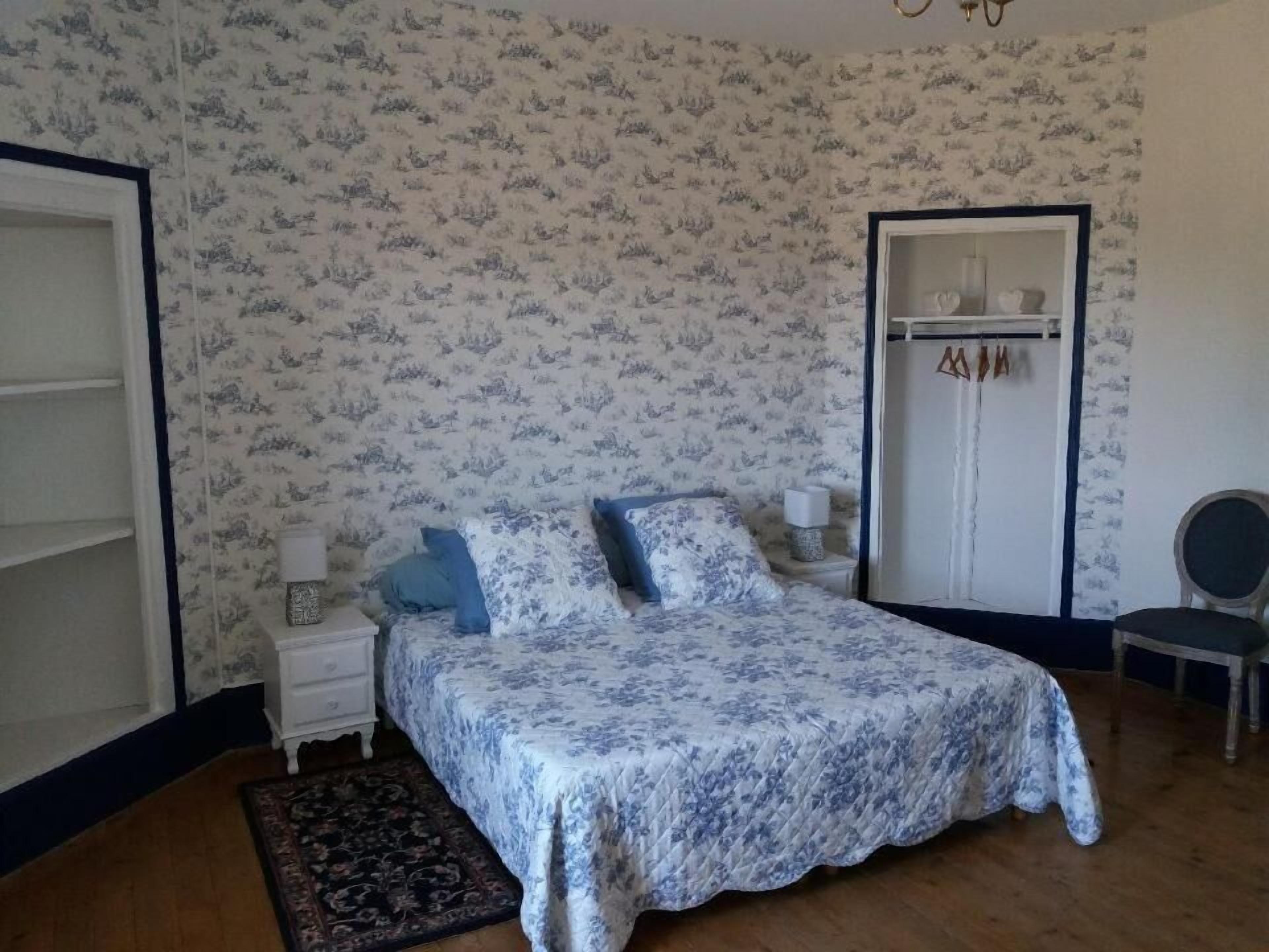 Une chambre à coucher comprenant un lit, des tables de chevet, une chaise et une armoire.