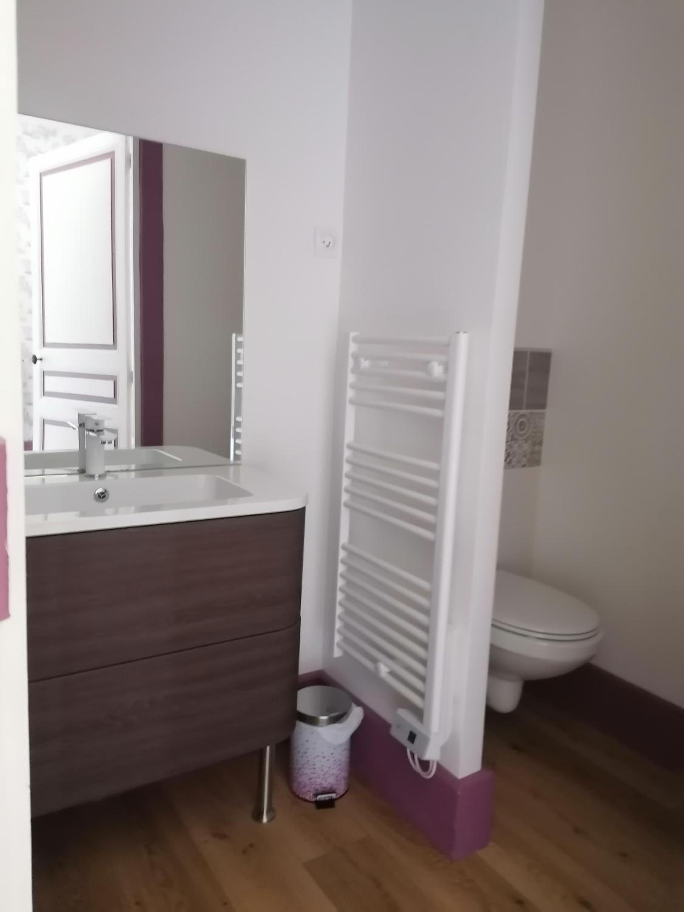Un bagno con un lavandino bianco, un mobile bagno in legno scuro, un WC bianco e un termosifone bianco.