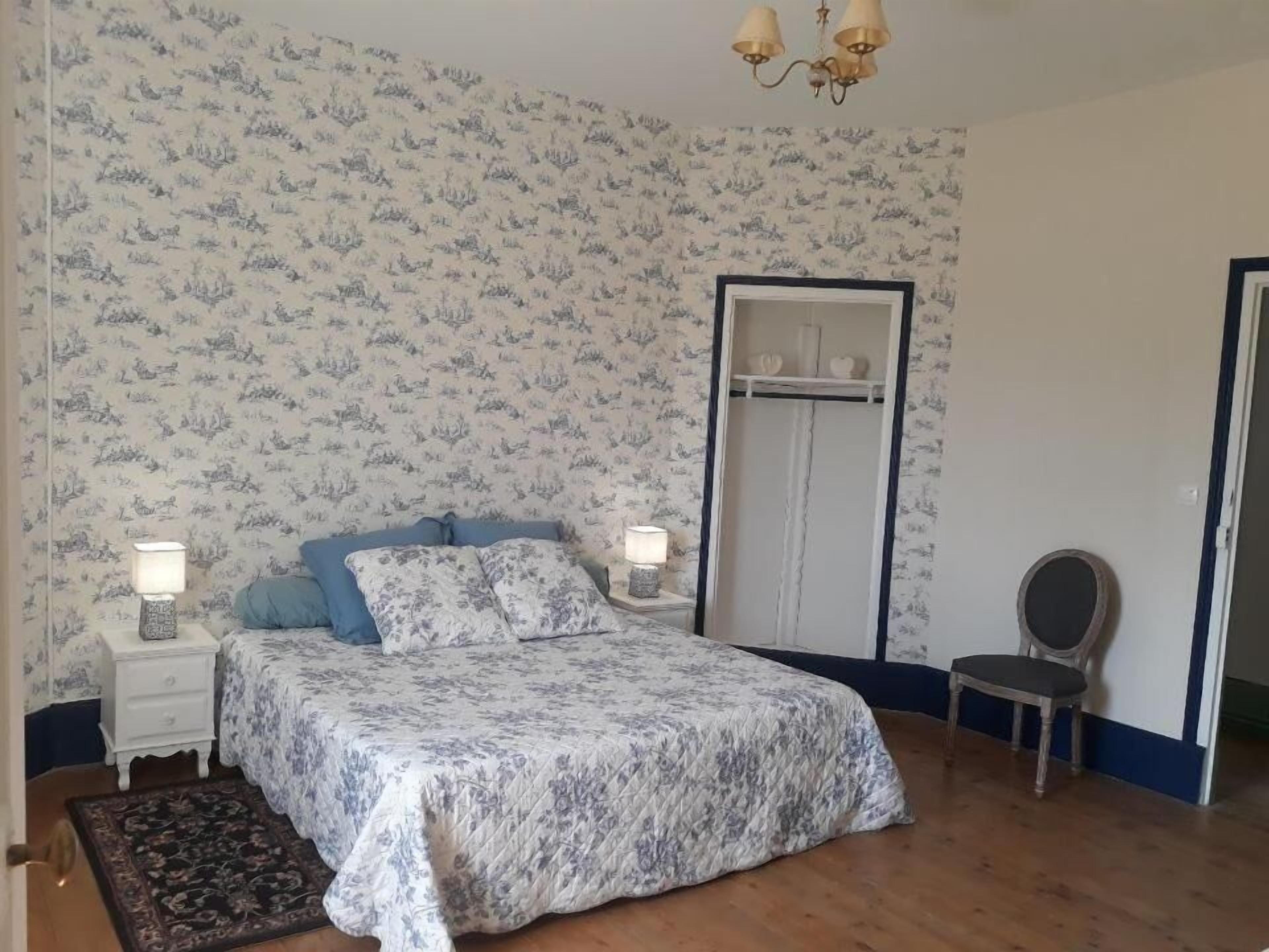 A bedroom with a bed, two bedside tables with lamps, a chair, and a wardrobe.