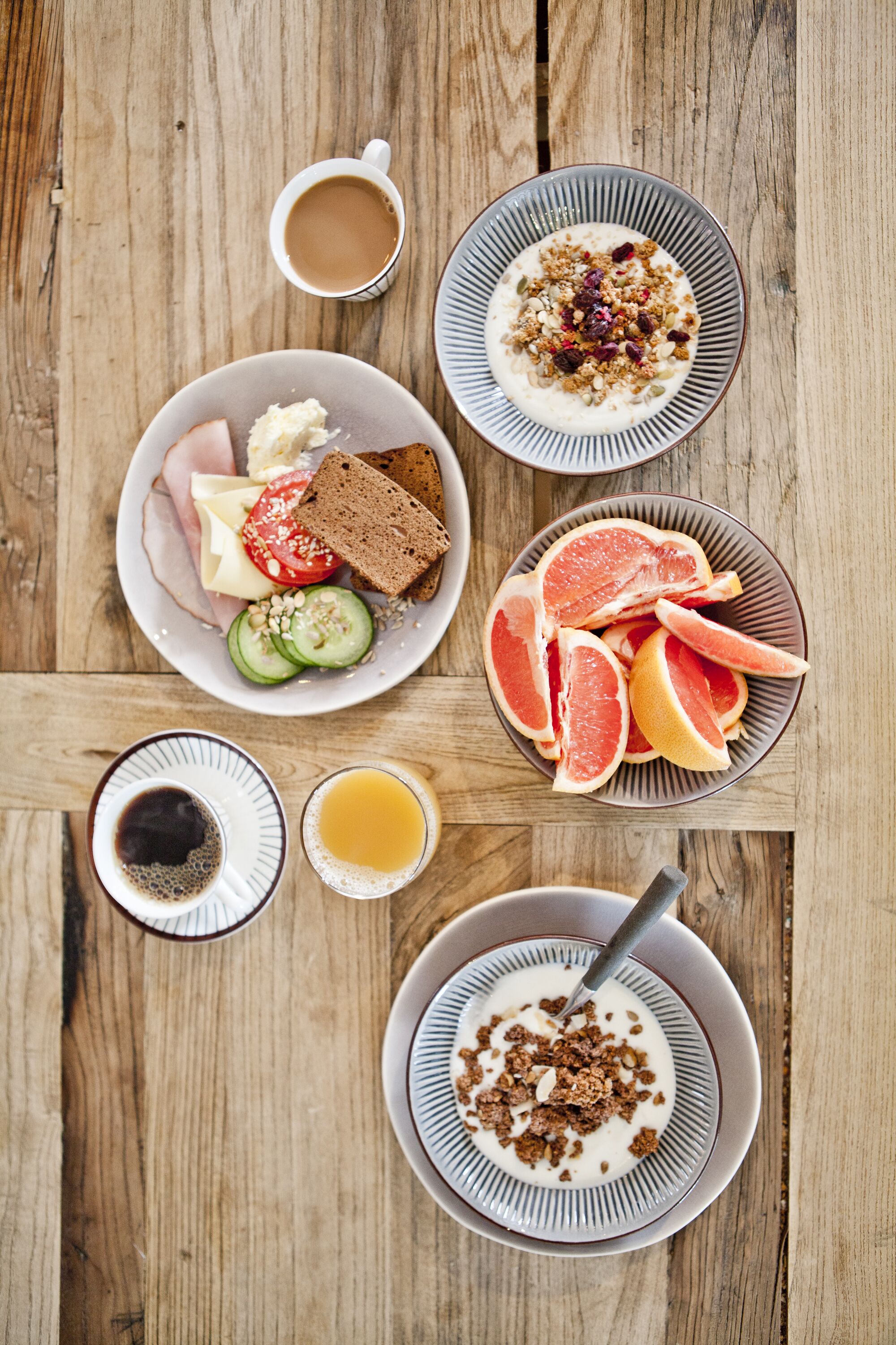 A breakfast table with plates of food, including toast, fruit, and yogurt.