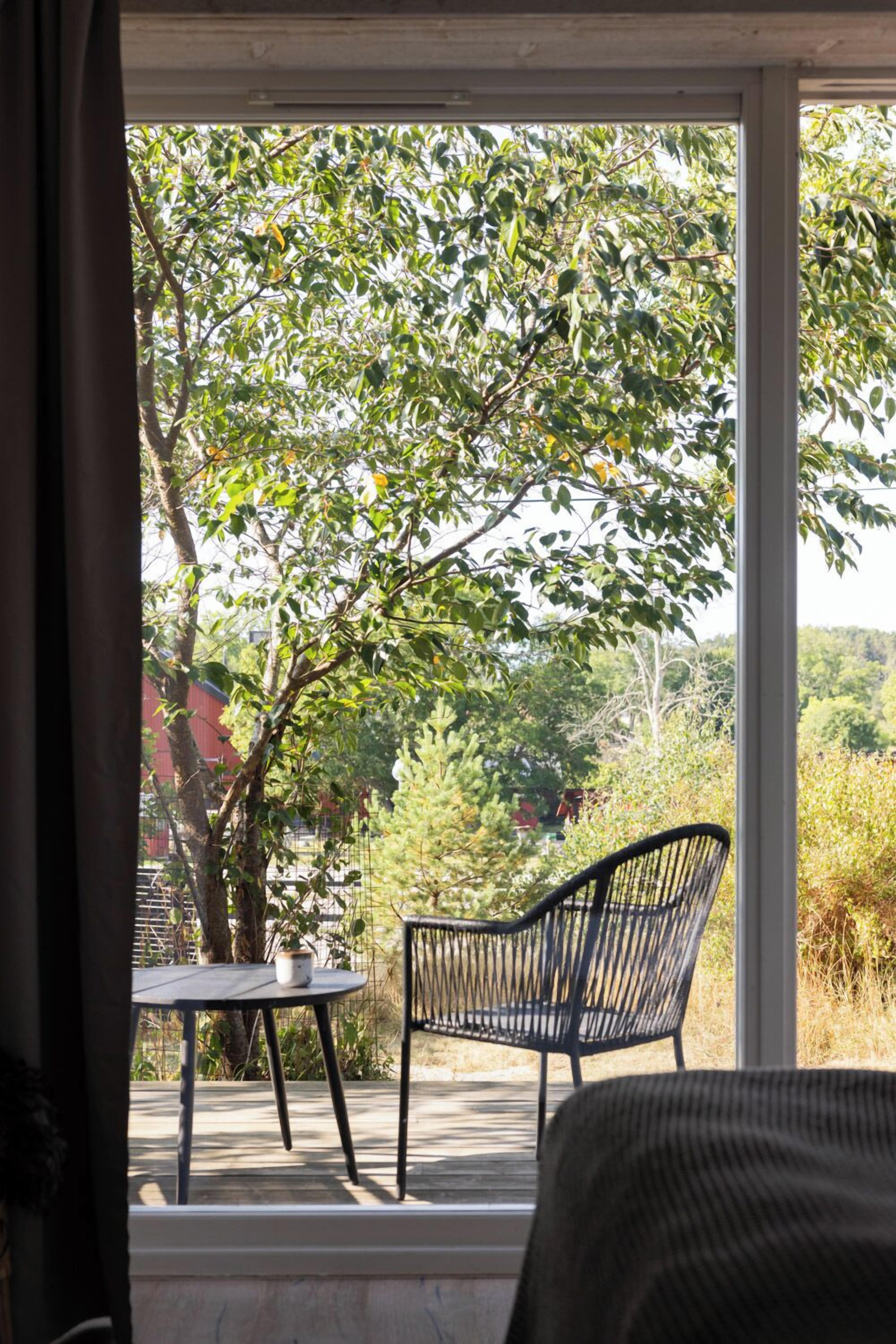 Una habitación con un ventanal grande, una mesa pequeña y una silla.