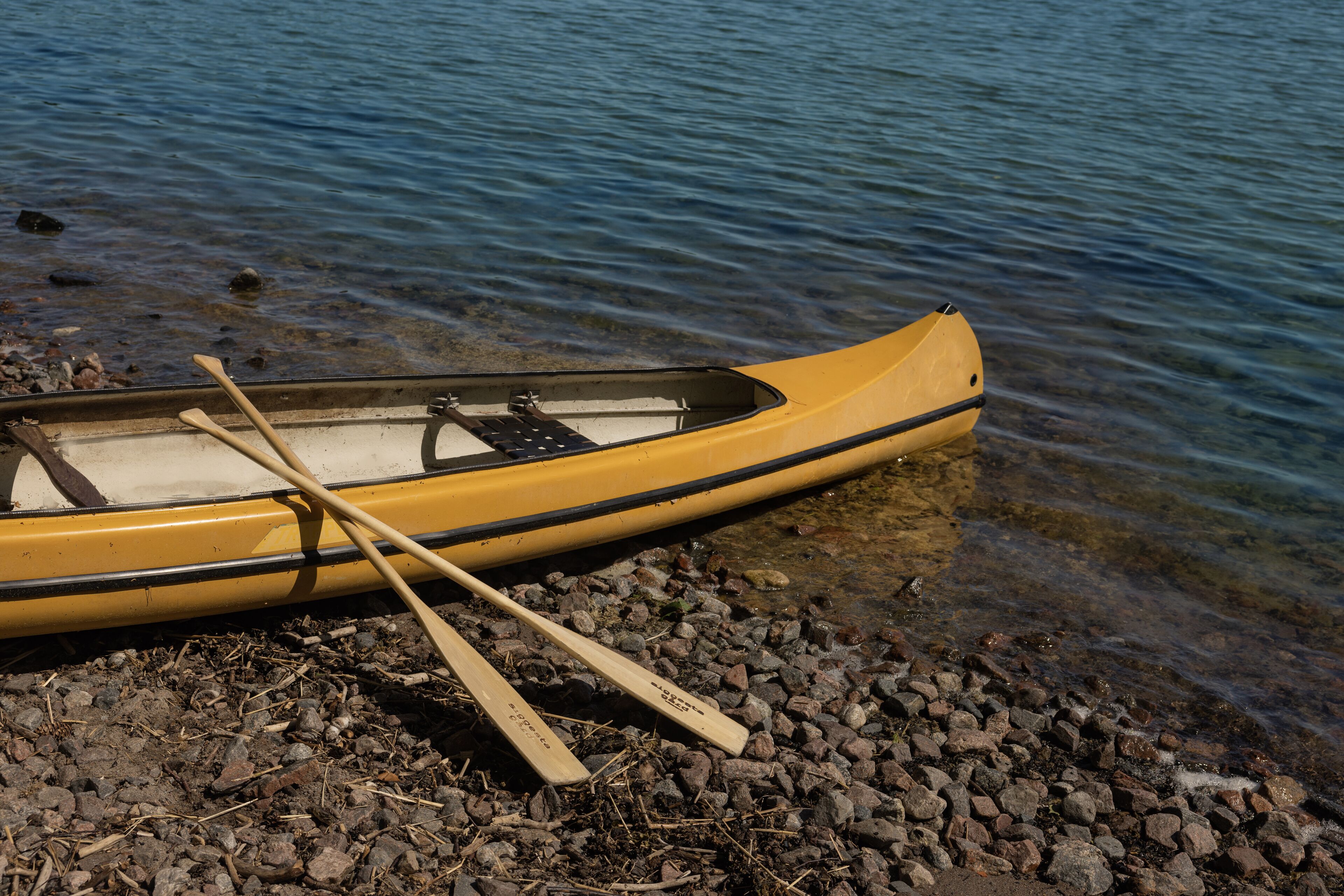 A canoe on a rocky shore with water.