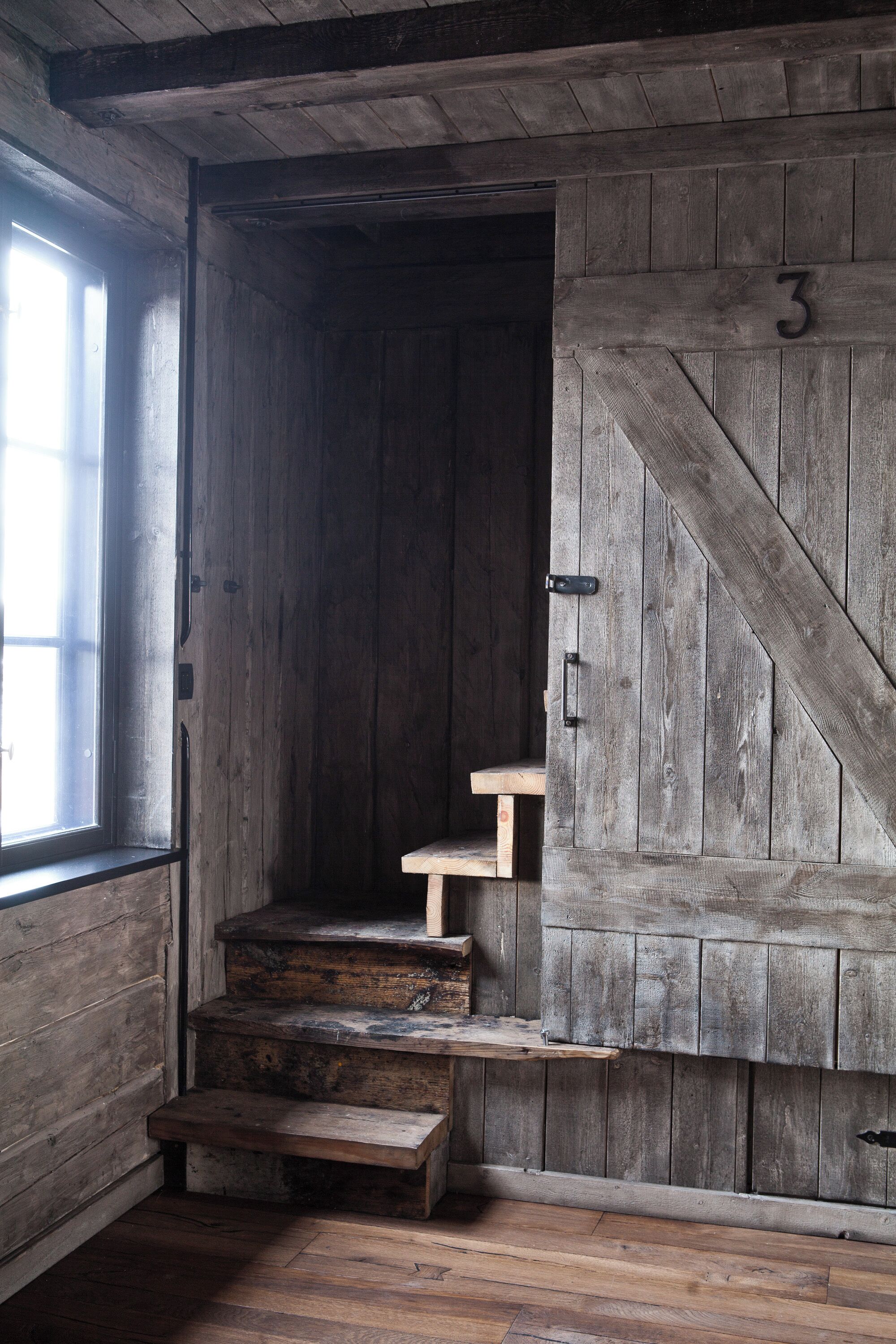 Eine rustikale Holztreppe führt zu einem erhöhten Bereich mit einem Fenster auf der linken Seite.