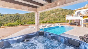 Un bain à remous avec vue sur une piscine et une colline.