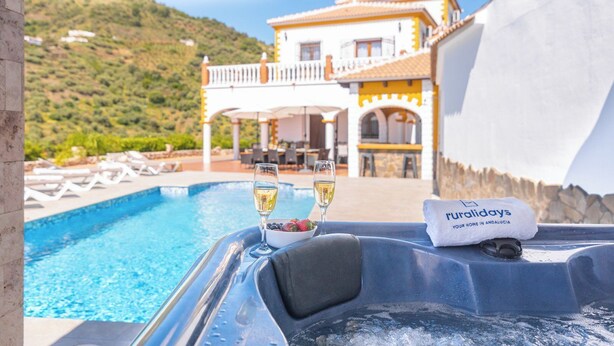 Une scène de bord de piscine avec un fauteuil de relaxation, un verre de vin blanc et un saladier de fruits. Une serviette sur laquelle est inscrit le mot « ruraldays » est posée sur le fauteuil.