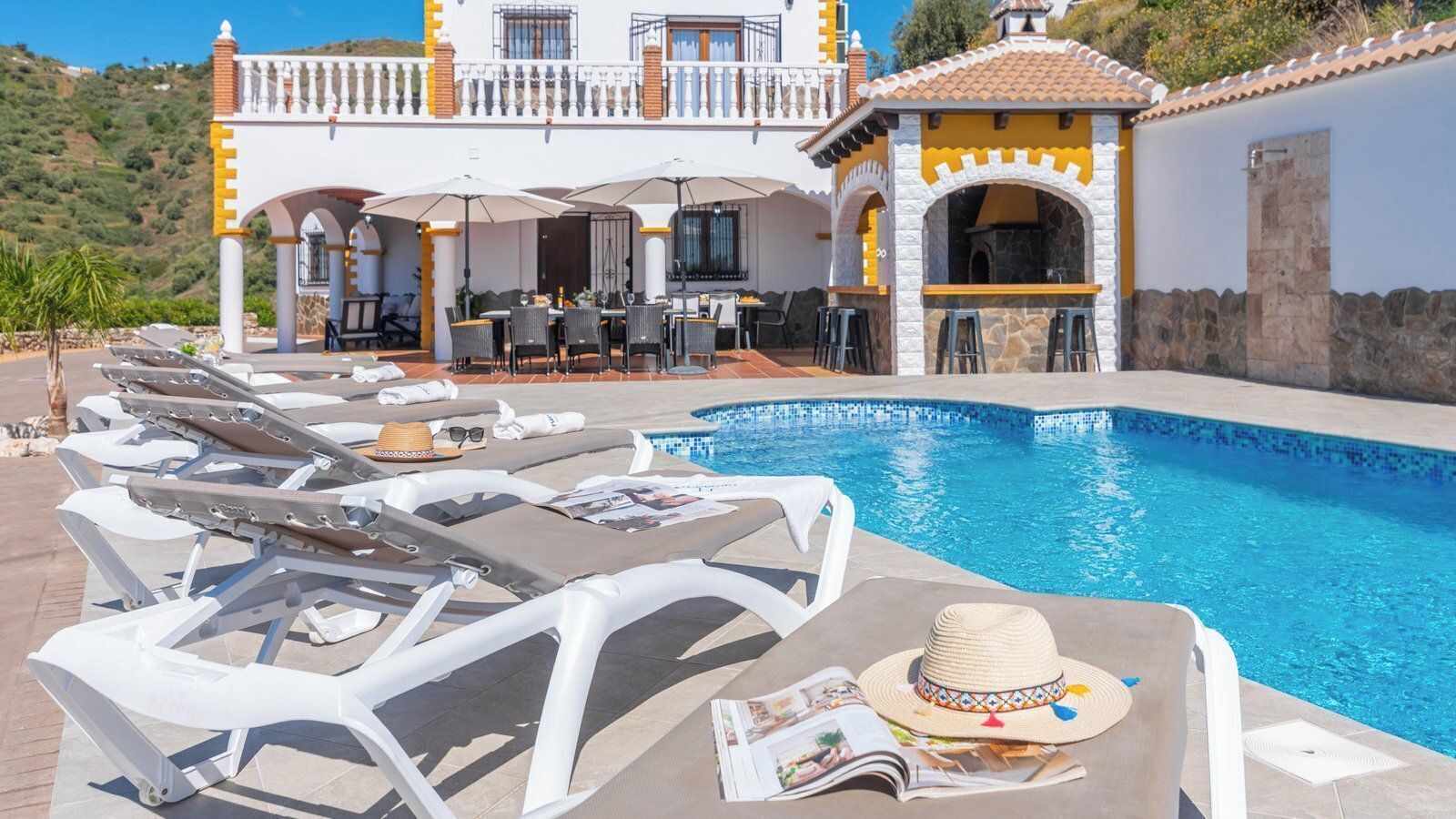 A poolside area with lounge chairs, a pool, and a building with a balcony.