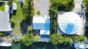 Luchtbeeld van een pand aan het water met een grote watertank, een steiger en een huis met balkon.