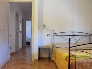Une chambre à coucher avec un lit, une table de chevet et une porte donnant sur une autre pièce.