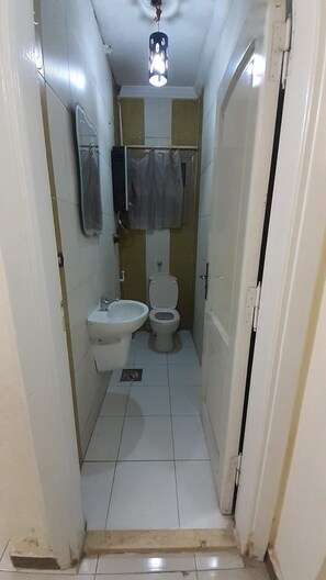 Un baño pequeño con inodoro, bidé y espejo sobre el lavabo.
