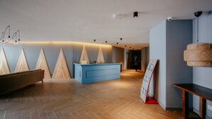 A modern reception area with a wooden reception desk, a blue counter, and a wooden boat model. - New Gudauri Block 4 - Ski4Life (Kazbegi)