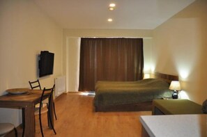 Une chambre d’hôtel comprenant un lit, un bureau avec une chaise, une télévision et une lampe.